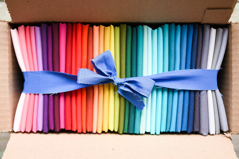 A package of folded rainbow coloured fabric bundled together.